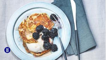 Pancakes with yoghurt and berries on a plate with a knife next to it