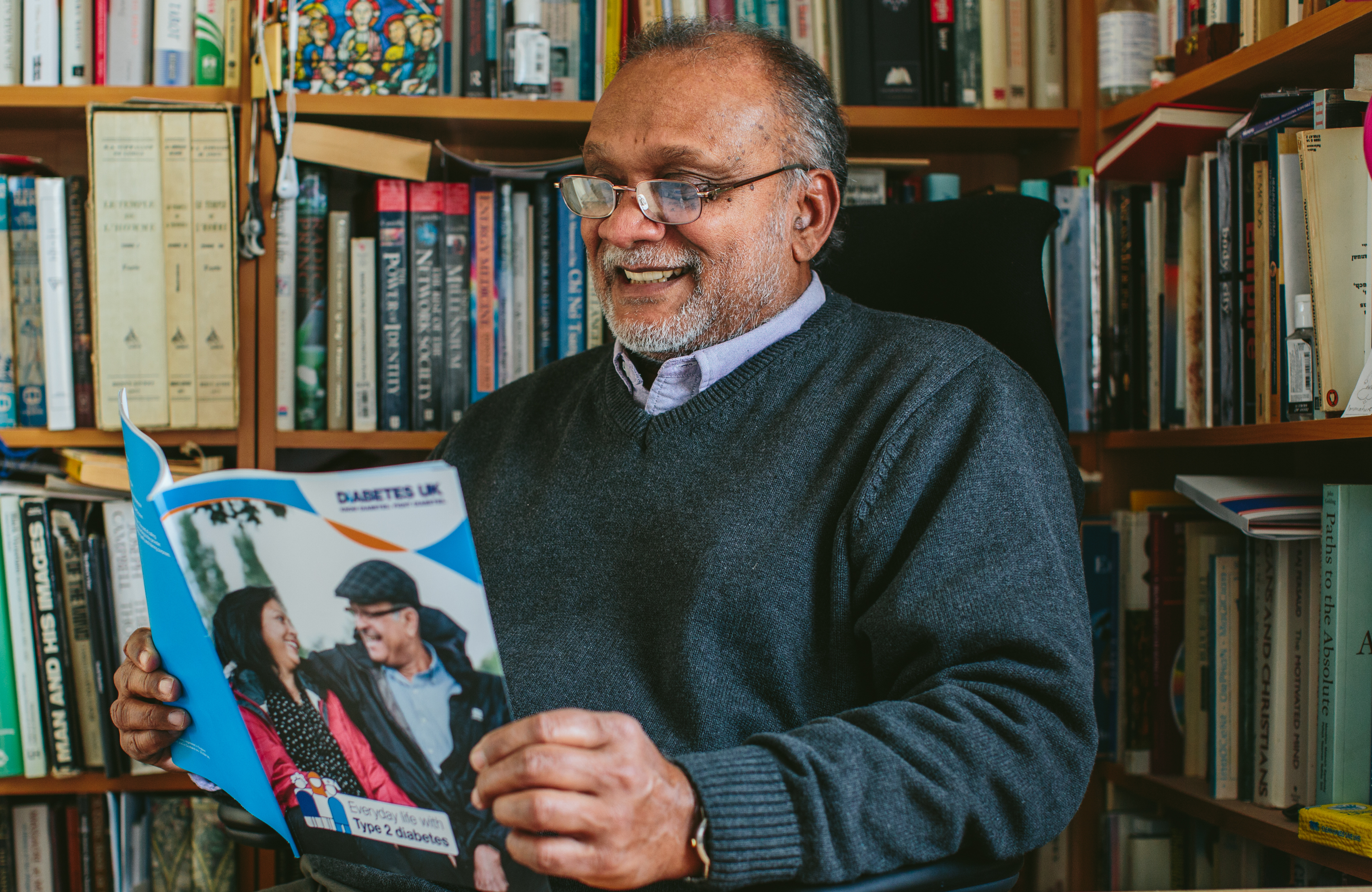 Man reading a leaflet in a library, smiling