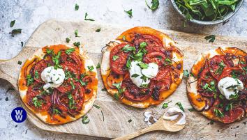 Three harissa tomato tarts on a wooden chopping board