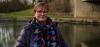 A photo of Joanne standing on a stone bridge by a river, smiling to camera