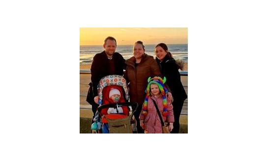 The Nye family standing in front of a beach at sunset, smiling to camera