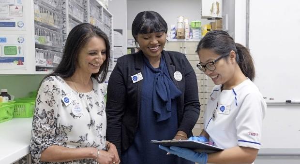 3 Tesco pharmacy workers chatting and looking at notes