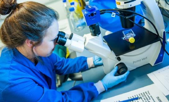 Women scientist looking down microscope