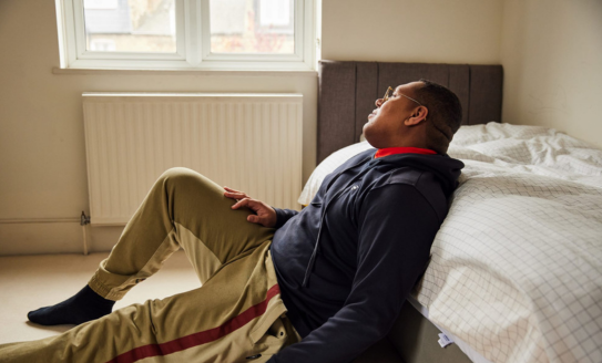 Man on floor of bedroom looking out of window 